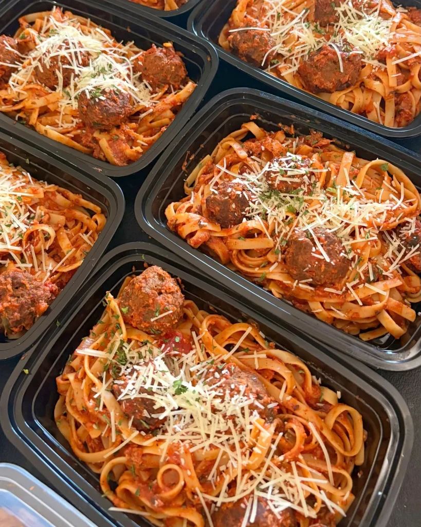 Containers of fettuccine with homemade meatballs, tomato sauce, parmesan and parsley
