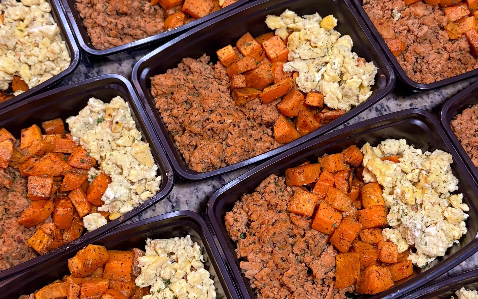 Rows of Breakfast Power Bowls in black containers: ground turkey, roasted sweet potatoes and fluffy eggs