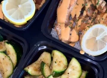 Salmon with zucchini, rice and lemon in meal prep containers
